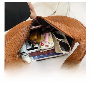 Interno spazioso della borsa tote intrecciata marrone con oggetti quotidiani e tasche