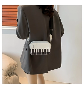 Detail view of piano key design crossbody bag with wide adjustable shoulder strap on model