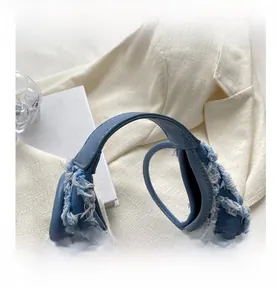 Close-up of denim moon bag featuring frayed fringe edges and a silver rotating buckle