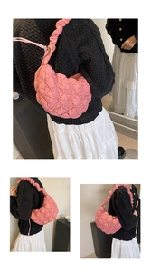 Detail of pink quilted crescent bag featuring textured fabric and ruched shoulder strap