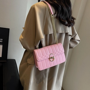 Schicke rosa gesteppte Umhängetasche mit goldener Hardware über einem Trenchcoat