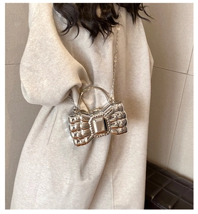 Silver bow knot evening clutch bag with metal chain shown on model in a modern room