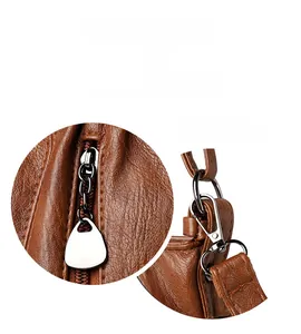 Detail of silver hardware and textured brown leather on women's crossbody bag
