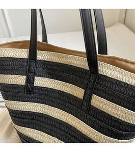 Detail of black and white striped straw tote with reinforced leather handle stitching