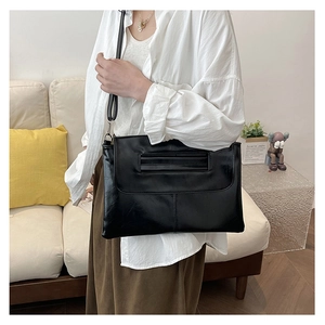 Detail of minimalist black faux leather crossbody bag with vintage wrinkled texture and strap