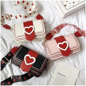 Détail de sacs à bandoulière avec motif cœur en blanc, rose et noir avec sangle large