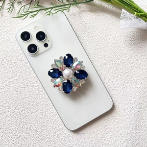 Close-up of luxury flower-shaped phone grip with blue crystals and a white pearl detail