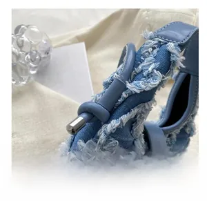 Detailed close-up of reinforced denim shoulder strap with knot and silver metal tip