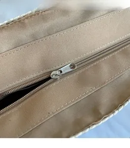 Close-up of smooth metal zipper and inner lining on a large straw bucket bag