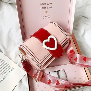 Détail du sac à bandoulière rose avec boucle cœur et boîte cadeau assortie