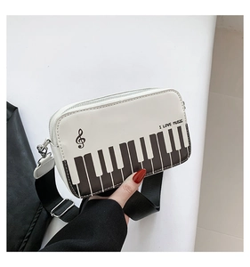 Detail view of square crossbody bag featuring piano keys pattern and I LOVE MUSIC text