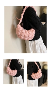 Detailed view of a pink quilted puff shoulder bag with heart patterns on a model