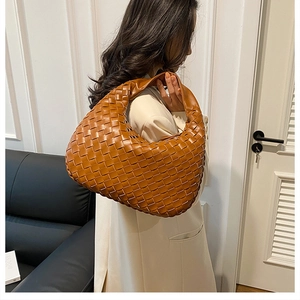 Brown hand-woven hobo bag in leather material shown on model in a modern interior