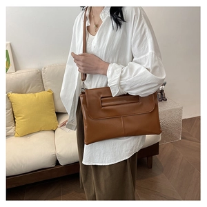 Brown faux leather envelope bag with unique cutout handle shown on a shoulder