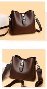 Detailed view of dark brown pebbled leather bucket bag with wide canvas strap