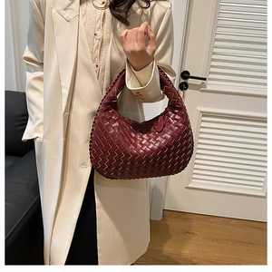 Detail of burgundy woven leather hobo bag with signature knot handle and premium texture