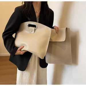 Detail of beige large tote bag set with metal ring handles and matching envelope pouch