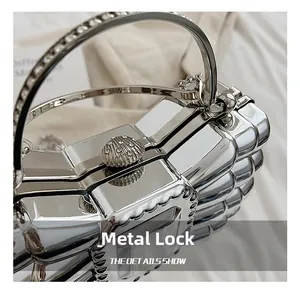 Detail of silver metallic evening clutch with shell-shaped rhinestone lock and wavy texture