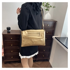 Golden metallic envelope clutch bag shown worn over the shoulder with thin strap