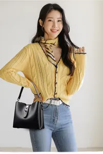 Detail of black pebbled leather bucket bag with metal buckle on casual outfit