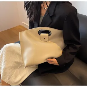Detail of off-white faux leather clutch with silver U-shaped handle and snap closure