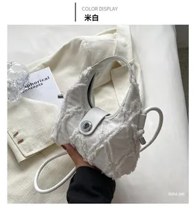 Detail view of off-white crescent bag with fringed quilted texture and silver twist lock