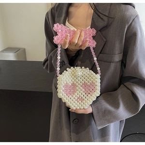 Detailed close-up of handmade pearl mini bag with pink heart motifs and bow detail