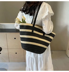 Detail of black and white striped woven straw tote bag with slim leather straps