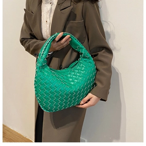 Detail of green woven hobo bag showing intricate leather weaving and white stitching contrast