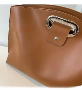 Detail of lychee pattern leather texture and polished silver metal buckle on tote bag