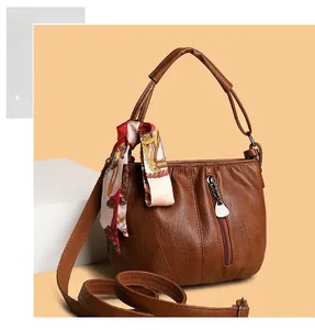 Close-up of brown PU leather handbag with pleated opening, zipper pocket and silk scarf