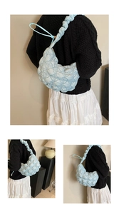 Detail of light blue quilted puffer shoulder bag with ruched strap on a female model
