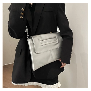 Silver metallic crossbody clutch bag with textured finish shown on a model