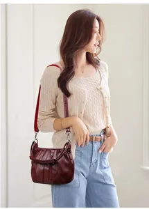 Close-up of wine red pleated leather crossbody bag with silver hardware and adjustable strap