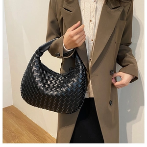 Detail of black woven PU leather hobo bag with intricate craft texture and wide handle