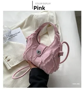 Detail of pink denim crescent bag featuring distressed fringe and metal swivel lock