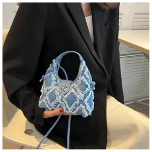 Close-up of light blue denim crescent bag featuring quilted frayed edges and metal clasp