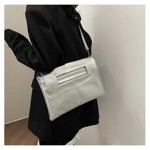 Detail showing the silver metallic shoulder bag with a rectangular flap and stitching