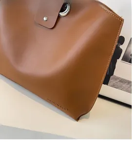Close-up of caramel brown leather tote bag with metal lock and embossed logo detail