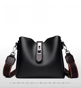 Detail of soft black leather bucket bag featuring silver buckle and striped fabric strap