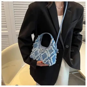 Close-up of blue denim crescent bag featuring quilted frayed edges and silver twist lock