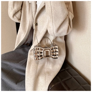 Close-up of a silver bow-shaped evening clutch bag with a crystal buckle and chain strap