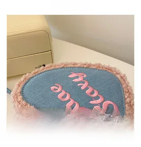 Détail d'un sac à main en jean bleu en forme de cœur avec garniture en fausse fourrure