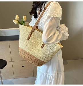 Detail of handwoven straw tote featuring leather handles and decorative cross stitching