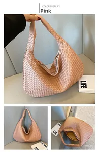 Dettaglio di una borsa hobo rosa intrecciata con trama geometrica e tracolla larga