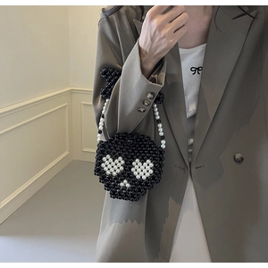 Close-up of handmade black beaded mini bag featuring white heart patterns and chain strap