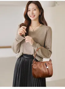 Detail of a brown oil wax leather handbag featuring a stylish heart-shaped metal zipper pull