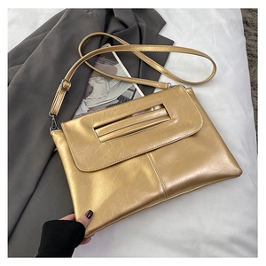 Detail of golden envelope bag with metallic pleated texture and slim adjustable strap