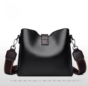 Back view of a black glossy bucket bag featuring a V-shaped opening and striped strap