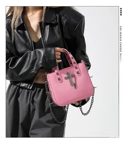 Pink punk handbag with metal rivets and cross charm shown with a black biker jacket